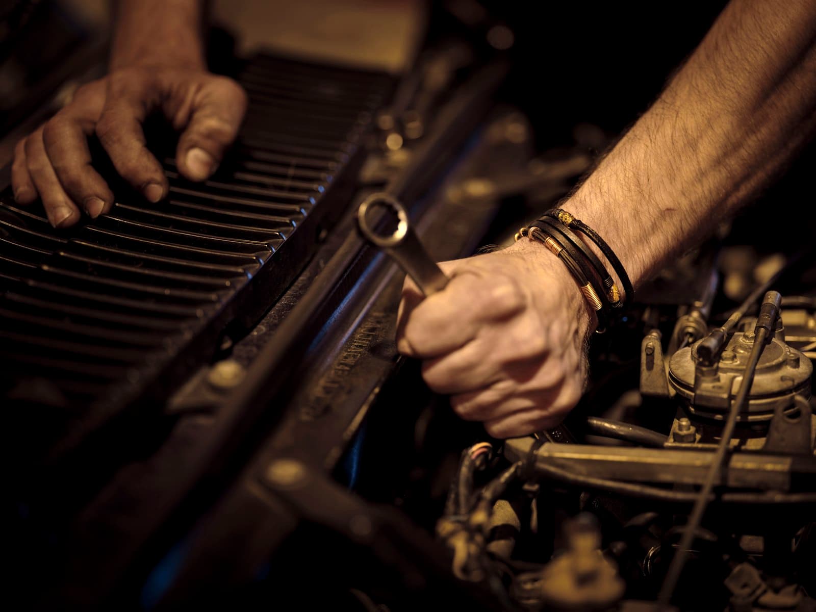 Hands fitting a part in a car engine with a spanner